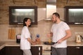 Happy young couple preparing breakfast, man fries broccoli, scrambled eggs. Smiling girl stands nearby. On self-isolation during