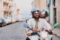 Happy young couple in protective hats are riding on vintage scooter in the Lisbon street Royalty Free Stock Photo