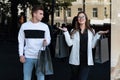 Happy young couple with purchases after successful shopping. Guy and girl with shopping bags next to showcase