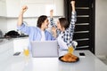 Happy young couple with raised arms of win celebrate looking on laptop in kitchen Royalty Free Stock Photo