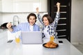 Happy young couple with raised arms of win celebrate looking on laptop in kitchen Royalty Free Stock Photo