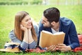 Happy young couple reading book in park on spring day Royalty Free Stock Photo