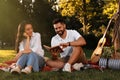 Happy young couple reading book on plaid in park Royalty Free Stock Photo