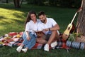 Happy young couple reading book on plaid in park. Summer picnic Royalty Free Stock Photo