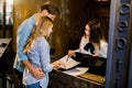 Happy young couple receiving tourist information at hotel reception. Young woman receptionist showing places of the city Royalty Free Stock Photo