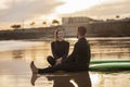 Happy Young Couple Relaxing On The Beach After Surfing Together Royalty Free Stock Photo