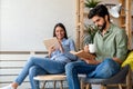 Happy young couple relaxing. Reading something on book and tablet computer. Royalty Free Stock Photo