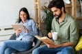 Happy young couple relaxing. Reading something on book and tablet computer. Royalty Free Stock Photo