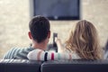 Happy young couple relaxing and watching TV at home.