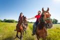 Happy young couple riding bay horses holding hands Royalty Free Stock Photo