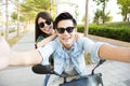 Happy young couple riding scooter and making selfie photo