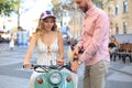 Happy young couple riding scooter in town. Handsome guy and young woman travel. Adventure and vacations concept Royalty Free Stock Photo