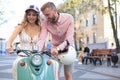 Happy young couple riding scooter in town. Handsome guy and young woman travel. Adventure and vacations concept Royalty Free Stock Photo