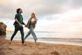 Happy young couple running on beach near sea, holding hands and smiling Royalty Free Stock Photo