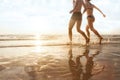 Happy young couple running to the sea on the beach at sunset, silhouettes of man and woman Royalty Free Stock Photo