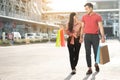 Happy young couple of shoppers walking in the shopping street towards and holding colorful shopping bags in hand. Concept of sale Royalty Free Stock Photo