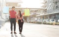 Happy young couple of shoppers walking in the shopping street towards and holding colorful shopping bags in hand. Concept of sale Royalty Free Stock Photo