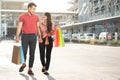 Happy young couple of shoppers walking in the shopping street towards and holding colorful shopping bags in hand. Concept of sale Royalty Free Stock Photo