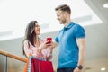 Young couple with shopping bags and smartphone talking in mall Royalty Free Stock Photo