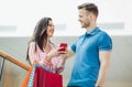 Young couple with shopping bags and smartphone talking in mall Royalty Free Stock Photo