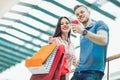 Young couple with shopping bags and smartphone talking in mall Royalty Free Stock Photo