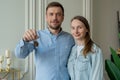 Happy young couple show new own house keys. Young smiling couple showing keys to new home hugging looking at camera. Royalty Free Stock Photo