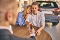 Happy cheerful girl getting a car key with handsome man in showroom. Business concept and car selling Royalty Free Stock Photo