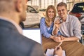 Happy cheerful girl getting a car key with handsome man in showroom. Business concept and car selling Royalty Free Stock Photo