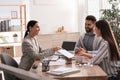 Happy young couple signing purchase contract in real estate agent`s office. Mortgage concept Royalty Free Stock Photo