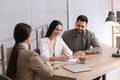 Happy young couple signing purchase contract in real estate agent`s office. Mortgage concept Royalty Free Stock Photo