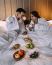 Happy young couple sitting in bed in morning and having breakfast Royalty Free Stock Photo