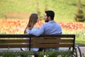 Happy young couple sitting on bench in park Royalty Free Stock Photo