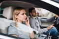 Happy young couple sitting in car, making phone call. Royalty Free Stock Photo