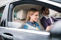 Happy young couple sitting in car, using smartphone. Royalty Free Stock Photo