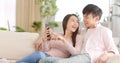 Happy young couple sitting on  couch and  looking at mobile phone Royalty Free Stock Photo