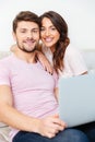 Happy young couple sitting on couch using laptop Royalty Free Stock Photo