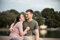 Happy young couple sitting on the dock by the lake, hugging Royalty Free Stock Photo