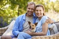 Happy young couple sitting with their pet dog in the garden Royalty Free Stock Photo