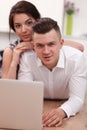 Happy young couple sitting together on the floor with laptop Royalty Free Stock Photo