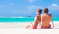 Happy young couple sitting on a tropical beach in