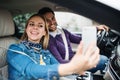 Happy young couple with smartphone sitting in car, taking selfie. Royalty Free Stock Photo