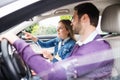 Happy young couple with smartphone sitting in car, talking. Royalty Free Stock Photo