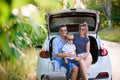 Couple with son having a coffee break while traveling in the countryside. A man and a woman are sitting in the trunk of Royalty Free Stock Photo