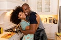 Happy young couple standing in the kitchen, embracing and smiling to camera Royalty Free Stock Photo