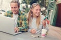 Happy young couple in street cafe, using phone and laptop Royalty Free Stock Photo