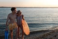 Happy young couple in swimsuits posing with swimming wheel, at beach during sunset. Royalty Free Stock Photo