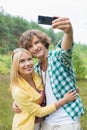 Happy young couple taking self portrait through cell phone in field Royalty Free Stock Photo
