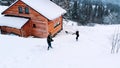 Happy young couple throwing snowballs on winter day in front of the wooden house Royalty Free Stock Photo