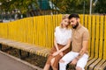 Happy young couple of tourists resting in city park sitting hugging with closed eyes on bench in summer day, enjoying Royalty Free Stock Photo