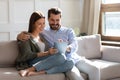 Happy young couple using computer tablet together, sitting on couch Royalty Free Stock Photo